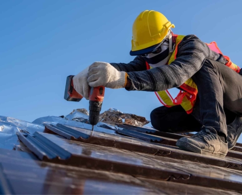 Image of a worker installing new tiles on a commercial roof.