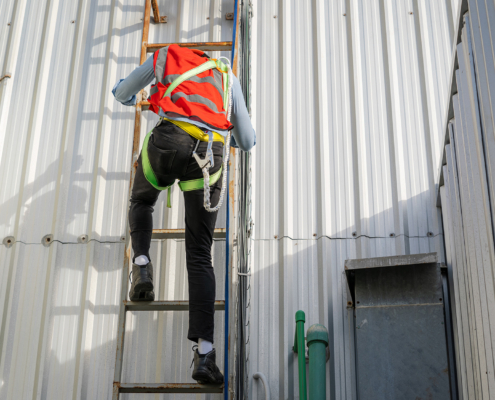 Roof inspector climbing ladder to commercial roof